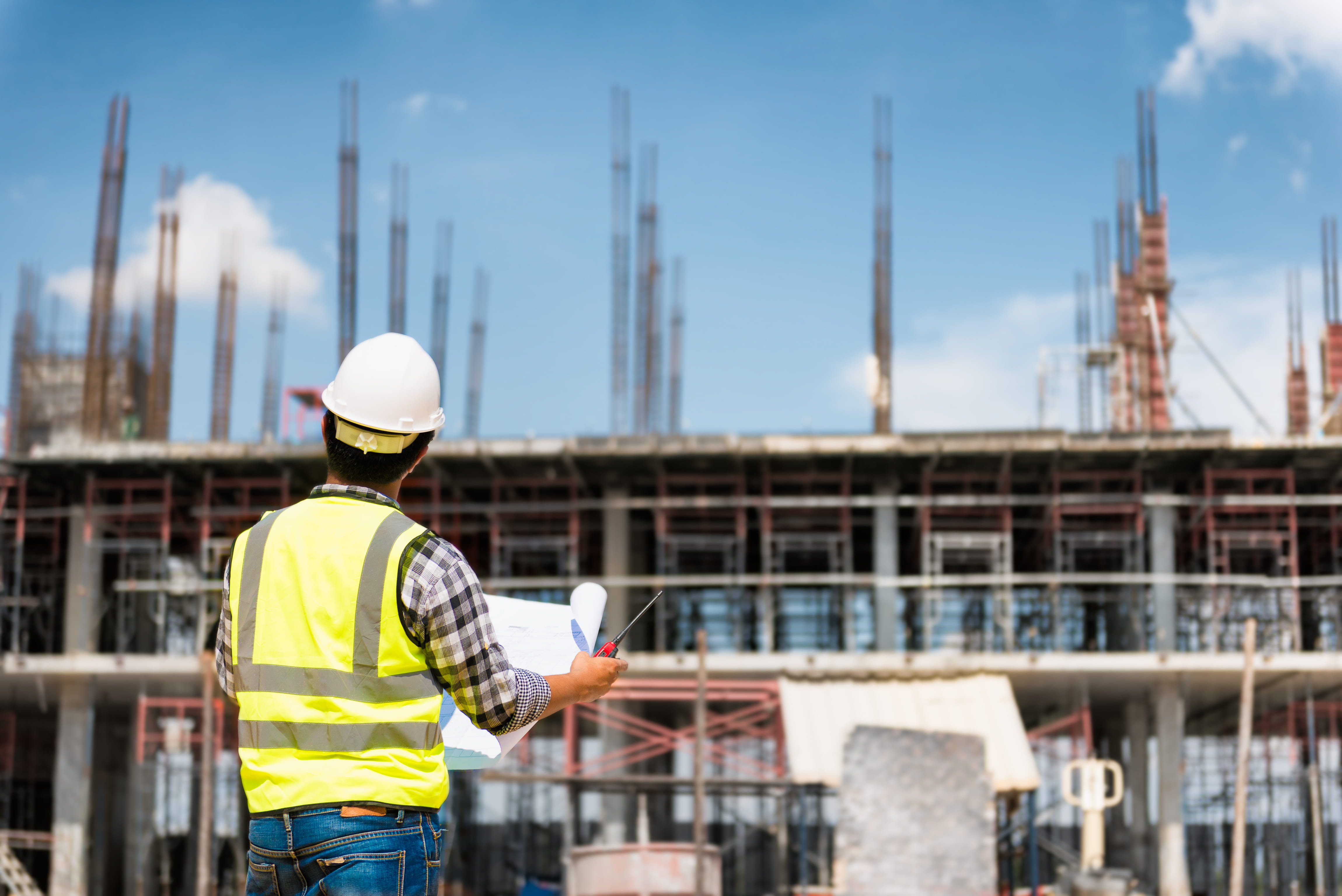 A construction worker in a high vis and hard hat looking at scaffolding