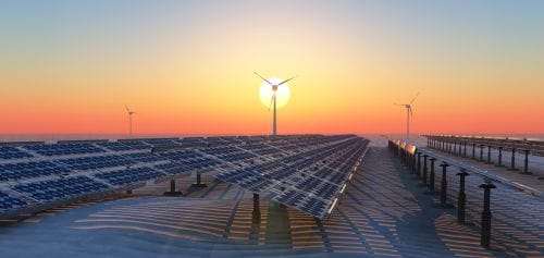 Wind turbines and solar panels at sunset
